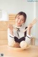 A woman holding a wooden spoon and a plate of food.