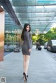 A woman in a gray suit is standing in front of a building.