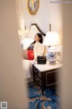 A woman sitting on a bed next to a lamp.