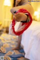 A woman in lingerie holding a red bag on a bed.