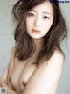 A naked asian woman with long brown hair posing for the camera.