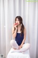 A woman sitting on a bed eating an apple.