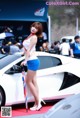 A woman standing next to a white sports car holding an umbrella.