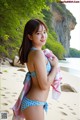 A woman in a blue and white bikini standing on a beach.