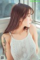 A woman with a tattoo on her arm looking out a window.