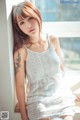 A woman in a white dress sitting on a window sill.