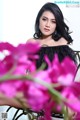 A woman sitting on a chair with pink flowers in front of her.