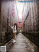 A woman standing in an alleyway with red lanterns hanging from the walls.