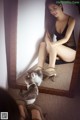 A woman sitting in front of a mirror with a cat.