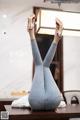 A woman in jeans and high heels is upside down on a table.