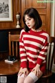 A woman sitting on a chair wearing a red and white striped sweater.