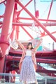 A woman standing in front of a ferris wheel with her arms outstretched.