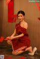 A woman in a red dress holding a red envelope.