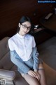 A woman wearing glasses sitting on a chair in a room.