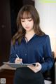 A woman in a business suit writing on a clipboard.