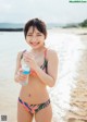 A woman in a bikini holding a bottle of water.