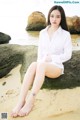 A woman sitting on a rock on the beach.