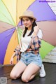 A woman sitting on the ground holding an umbrella.