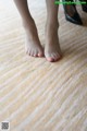 A woman's bare feet with red nail polish on a carpet.