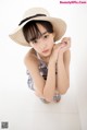 A young woman wearing a straw hat sitting on the floor.