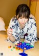 A woman in a kimono playing a game on a bed.