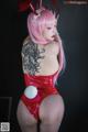 A woman in a red bodysuit with pink hair and bunny ears.