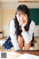 A young woman sitting at a desk in a classroom.